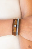 Brown leather strands layer across the wrist. Infused with silver chain and white rhinestone accents, brown cording knots around a leather strand, securing a solitaire white rhinestone in place for a whimsical finish. Features an adjustable clasp closure. Sold as one individual bracelet.  P9DI-URBN-056XX