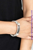 Stamped in the word, "Blessed", a shiny silver plate is studded in place along a dainty gray leather band for a whimsical look. Features an adjustable snap closure. Sold as one individual bracelet.  P9WD-SVXX-156XX