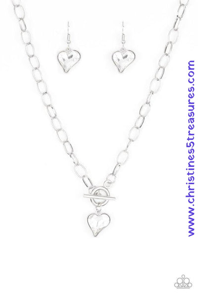 Cut into a whimsical heart shape, a glittery white gem swings from the bottom of a glistening silver chain below the collar for a charming look. Features a toggle closure. Sold as one individual necklace. Includes one pair of matching earrings.  P2WH-WTXX-222XX