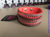 Shiny silver studs and rows of smoky and glittery white rhinestones are encrusted along strips of orange suede, creating sassy shimmer around the wrist. Features an adjustable snap closure. Sold as one individual bracelet.  P9DI-UROG-025XX