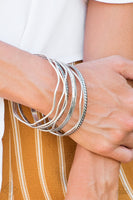 "Zesty Zimbabwe" (P9BA-SVXX-021HD)  Stamped in tribal inspired patterns, round and wavy silver bangles stack across the wrist for a seasonal look. Sold as one set of seven bracelets.