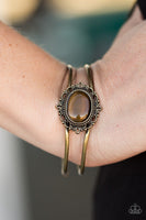 A glassy brown moonstone is pressed into a frilly brass frame, creating a whimsical center piece. The bangle-like bars curl around the wrist, creating an airy piece. Features an adjustable hinged clasp. Sold as one bracelet. P9WH-BRXX-075XX