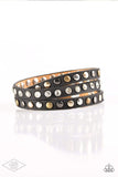 A skinny strip of black leather is encrusted in sections of glittery white rhinestones and flat brass, gold, and silver studs. The elongated band double wraps around the wrist for a fierce one-of-a-kind look. Features an adjustable snap closure. Sold as one individual bracelet.  P9DI-URBK-134XX