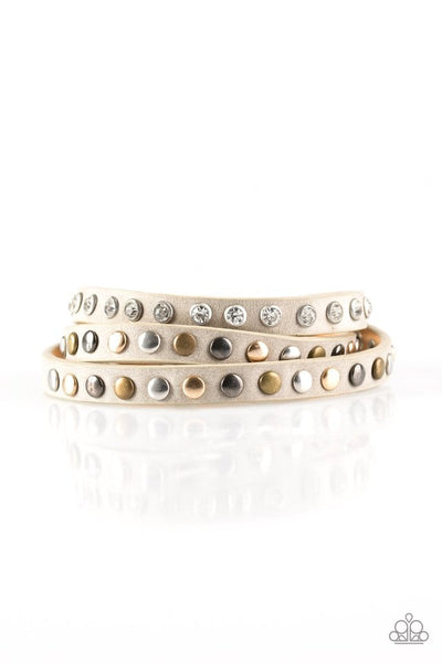 A skinny strip of tan leather is encrusted in sections of glittery white rhinestones and flat brass, gold, and silver studs. The elongated band double wraps around the wrist for a fierce one-of-a-kind look. Features an adjustable snap closure. Sold as one individual bracelet.  P9DI-URBN-058XX