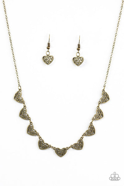 Heart-shaped filigree dances along the centers of shimmery brass heart frames. The airy frames delicately connect below the collar for a chic finish. Features an adjustable clasp closure. Sold as one individual necklace. Includes one pair of matching earrings.  P2WH-BRXX-114XX