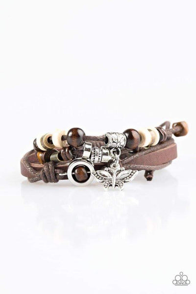 Mismatched metal beads and wooden accents are threaded along strands of brown twine and leather, creating earthy layers. A silver butterfly charm swings from the wrist, adding a whimsical finish to the urban palette. Features an adjustable sliding knot closure. Sold as one individual bracelet. P9UR-BNXX-309XX