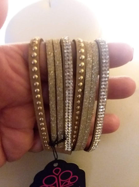 Strands of glistening gold studs, glittery aurum rhinestones, and brown suede dusted in glitter wrap around the wrist, creating mismatched shimmer. The elongated band allows for a trendy double wrap design. Features an adjustable snap closure. Sold as one individual bracelet.  P9DI-URGD-007XX