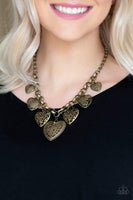 Swirling with mismatched filigree details, ornate brass heart frames swing from the bottom of a brass chain below the collar for a vintage look. Features an adjustable clasp closure. Sold as one individual necklace. Includes one pair of matching earrings.  P2WH-BRXX-157XX