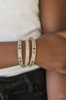 A skinny strip of tan leather is encrusted in sections of glittery white rhinestones and flat brass, gold, and silver studs. The elongated band double wraps around the wrist for a fierce one-of-a-kind look. Features an adjustable snap closure. Sold as one individual bracelet.  P9DI-URBN-058XX