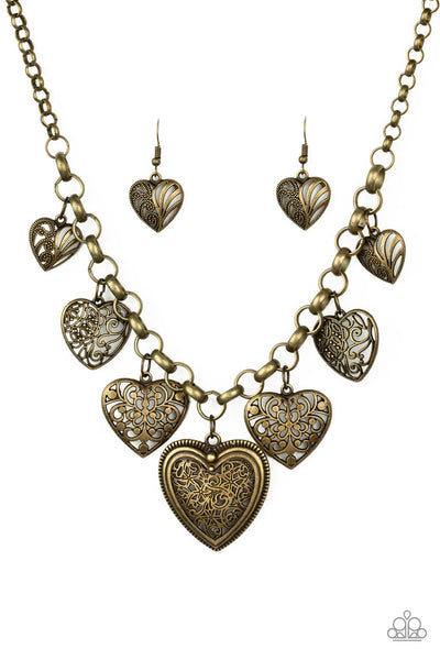 Swirling with mismatched filigree details, ornate brass heart frames swing from the bottom of a brass chain below the collar for a vintage look. Features an adjustable clasp closure. Sold as one individual necklace. Includes one pair of matching earrings.  P2WH-BRXX-157XX