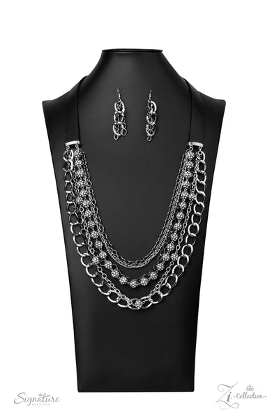 Attached to two strips of black leather, strands of bedazzled white rhinestone encrusted silver beads drape between an exaggerated display of mismatched silver and gunmetal chains down the chest. With its edgy sparkle, grunge meets glamour in this heart-stopping statement-maker. Features an adjustable clasp closure. Sold as one individual necklace. Includes one pair of matching earrings.  Named after 2020 Rock the Runway winner, Arlingto L.  Z2009