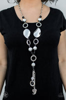 BLOCKBUSTER  Long chain of black crystalized beads, curved plates of silver with a pearly finish, and chunky silver rings lead down to a tassel of chains and charms, including a crescent moon and a heart. Sold as one individual necklace. Includes one pair of matching earrings.  P2RE-BKSV-019XX