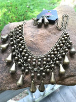 2018 June Fashion Fix Exclusive Threaded along metallic rods, stacked brass beads give way to shimmery brass teardrops. The edgy fringe flawlessly drapes beneath the collar, creating a sassy tapered fringe. Features an adjustable clasp closure. Sold as one individual necklace. Includes one pair of matching earrings.