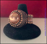 2018 October Fashion Fix Exclusive A pearly copper bead is pressed into the center of a stacked copper frame. Infused with classic copper studs and filigree detail, faceted copper studs spin around the pearly center, adding edgy shimmer to the dramatic centerpiece. Features a stretchy band for a flexible fit. Sold as one individual ring. P4RE-CPXX-086XX