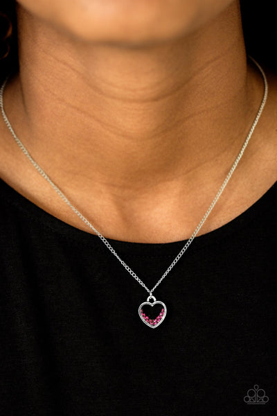 A glistening ribbon of silver curls into a romantic heart-shaped pendant below the collar. Glittery pink rhinestones dust the inside of the whimsical frame, adding refined shimmer to the timeless palette. Features an adjustable clasp closure. Sold as one individual necklace. Includes one pair of matching earrings.  P2DA-PKXX-095XX