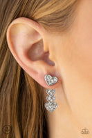 A white rhinestone encrusted silver heart attaches to a double-sided post, designed to fasten behind the ear. Stacked in gradually increasing white rhinestone encrusted heart frames, the glittery double-sided post peeks out beneath the ear for a charming look. Earring attaches to a standard post fitting. Sold as one pair of double-sided post earrings.  P5PO-WTXX-217XX