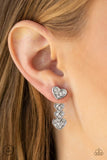 A white rhinestone encrusted silver heart attaches to a double-sided post, designed to fasten behind the ear. Stacked in gradually increasing white rhinestone encrusted heart frames, the glittery double-sided post peeks out beneath the ear for a charming look. Earring attaches to a standard post fitting. Sold as one pair of double-sided post earrings.  P5PO-WTXX-217XX