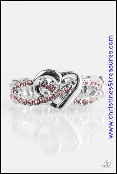 Encrusted in glittery pink rhinestones, silver ribbons crisscross across the finger, creating a dainty band. A glistening silver heart adorns the center of the band for a romantic finish. Features a dainty stretchy band for a flexible fit.  P4RE-PKXX-118XX