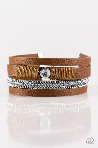 Brown leather strands layer across the wrist. Infused with silver chain and white rhinestone accents, brown cording knots around a leather strand, securing a solitaire white rhinestone in place for a whimsical finish. Features an adjustable clasp closure. Sold as one individual bracelet.  P9DI-URBN-056XX
