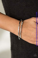 Featuring elegant round and emerald style cuts, glittery white rhinestones are pressed into two shimmery silver bangles for a refined look. Sold as one set of two bracelets.  P9RE-WTXX-197XX