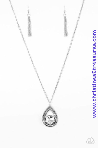 An oversized white rhinestone is nestled inside the bottom of a glistening silver teardrop radiating with studded textures. The dramatic pendant swings from the bottom of a lengthened silver chain for a regal look. Features an adjustable clasp closure. Sold as one individual necklace. Includes one pair of matching earrings.  P2RE-WTXX-350XX