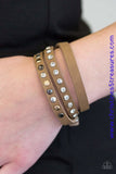 A skinny strip of brown leather is encrusted in sections of glittery white rhinestones and flat gold, gunmetal, and silver studs. The elongated band double wraps around the wrist for a fierce one-of-a-kind look. Features an adjustable snap closure. Sold as one individual bracelet.  P9DI-URBN-050XX