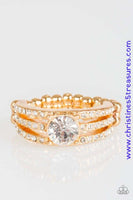 Encrusted in dainty white rhinestones, glistening gold bars layer across the finger, coalescing into a gorgeous band. A glittery white rhinestone is pressed into the center of the bands, creating a refined centerpiece. Features a dainty stretchy band for a flexible fit. Sold as one individual ring.  P4RE-GDXX-137XX