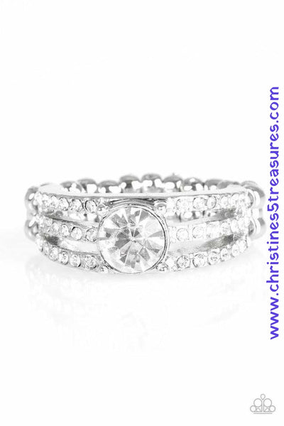 Encrusted in dainty white rhinestones, glistening silver bars layer across the finger, coalescing into a gorgeous band. A glittery white rhinestone is pressed into the center of the bands, creating a refined centerpiece. Features a dainty stretchy band for a flexible fit. Sold as one individual ring.  P4RE-WTXX-238XX