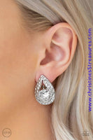 An oversized white rhinestone is nestled inside a hammered silver teardrop, creating a regal frame. Earring attaches to a standard clip-on fitting. Sold as one pair of clip-on earrings.  P5CO-WTXX-088XX