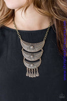 Gradually decreasing in size down the chest, decorative brass crescent plates connect into a bold pendant. Dotted in dainty studs, teardrop brass frames swing from the bottom of the tribal inspired pendant for a fierce finish. Features an adjustable clasp closure. Sold as one individual necklace. Includes one pair of matching earrings.  P2TR-BRXX-082XX