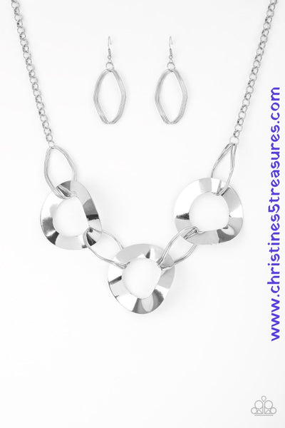 Featuring slightly warped surfaces, asymmetrical silver hoops link with reflective silver rings below the collar for a modern look. Features an adjustable clasp closure. Sold as one individual necklace. Includes one pair of matching earrings.   P2ED-SVXX-124XX