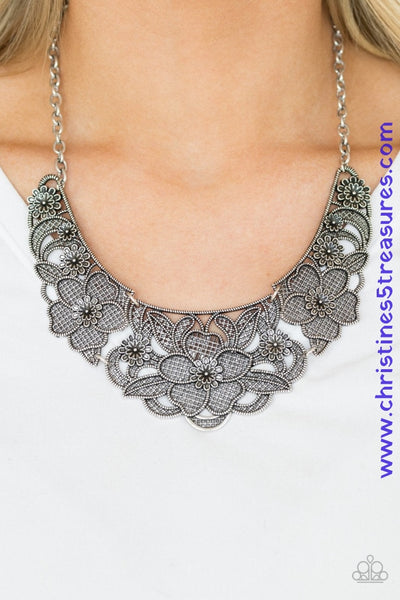 Featuring lattice-like patterns, shimmery silver flowers bloom below the collar for a seasonal look. Features an adjustable clasp closure. Sold as one individual necklace. Includes one pair of matching earrings.   P2ED-SVXX-119XX