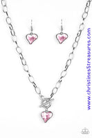 Cut into a whimsical heart shape, a glittery pink gem swings from the bottom of a glistening silver chain below the collar for a charming look. Features a toggle closure. Sold as one individual necklace. Includes one pair of matching earrings.  P2WH-PKXX-326XX