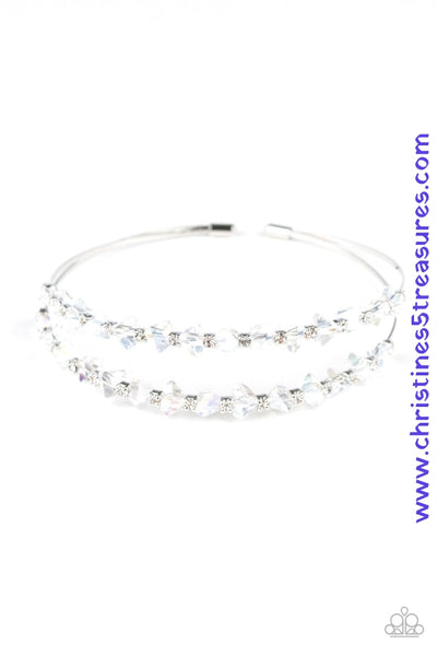 Featuring jagged cuts, a collection of faceted iridescent gems and dainty white rhinestones are encrusted along the tops of two silver wires, coalescing into a glamorous cuff. Sold as one individual bracelet.  P9RE-WTXX-332XX