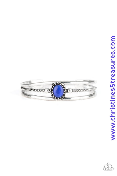 Smooth silver bars flank a textured silver band, coalescing into a layered cuff. A glowing blue cat's eye stone is pressed into the center of the cuff for a whimsical finish. Featured inside The Preview at ONE Life! Sold as one individual bracelet.  P9WH-BLXX-215XX
