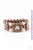 Pinched between white rhinestone encrusted frames, white rhinestone encrusted rings, crystal-beads, and brown pearls are threaded along elastic stretchy bands for a glamorous look. Sold as one individual bracelet.  P9RE-BNXX-092XX