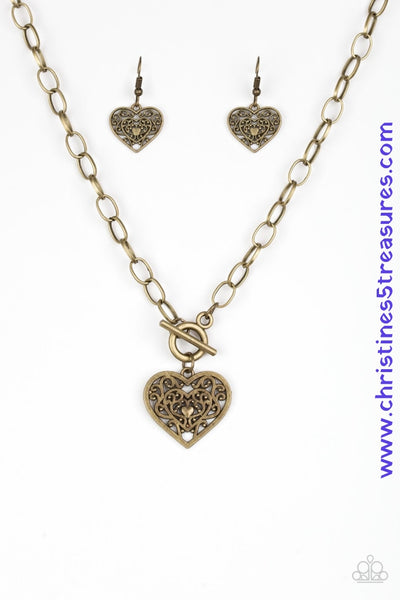 Brushed in an antiqued finish, brass filigree climbs a heart-shaped frame, creating a vintage inspired pendant below the collar. Features a toggle closure. Sold as one individual necklace. Includes one pair of matching earrings.   P2WH-BRXX-136XX